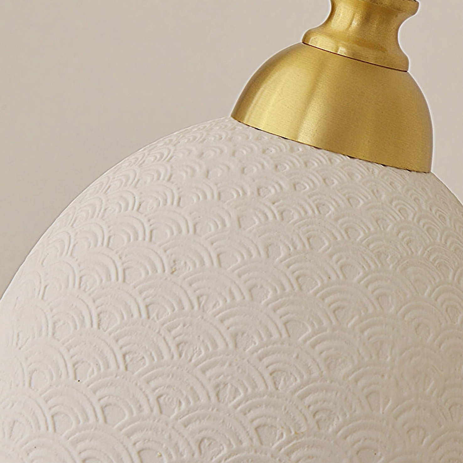 Close-up of embossed scale-pattern textured ceramic lamp shade with brass gold mounting