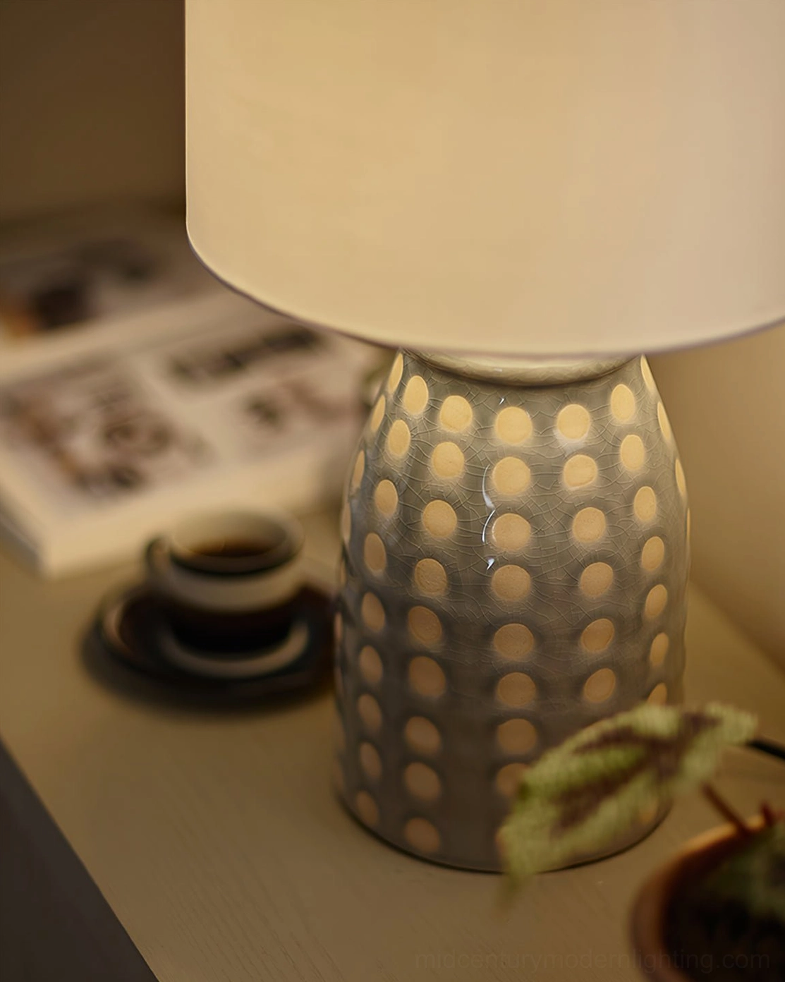 Ceramic patterned table lamp illuminated on bedside table creating warm ambient glow in bedroom interior design