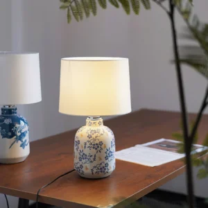 Pair of Avalyn ceramic table lamps with bird and floral prints on wooden office desk with green plant decor