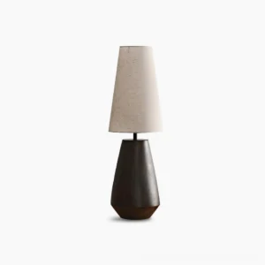 Ceramic tapered table lamp with rust-colored matte finish and beige fabric shade on white background, showcasing minimalist mid-century modern design