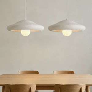 Two Chalk pendant lights hanging over wooden dining table with warm glow in neutral Japandi interior