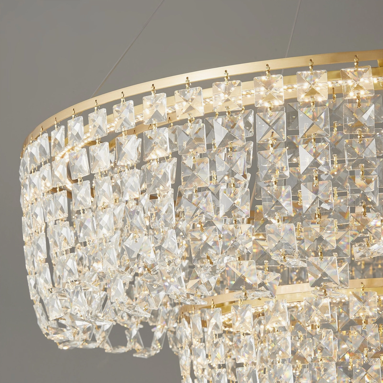 Close-up detail of chandelier crystal pendants and brushed brass mounting hardware