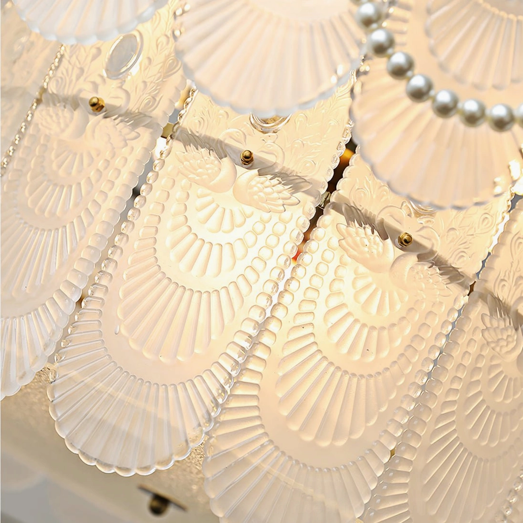 Close-up macro detail of chandelier frosted glass shade with embossed shell pattern, cameo carvings, and gold metal mounting hardware