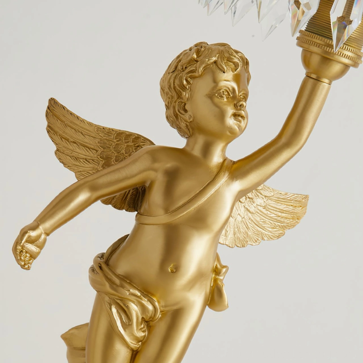 Close-up detailed view of hand-polished brass cherub sculpture with intricately carved wing details and facial features