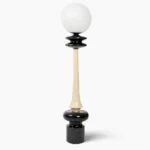 Chess floor lamp frontal view showing black and cream dual-tone sculptural design with frosted glass sphere