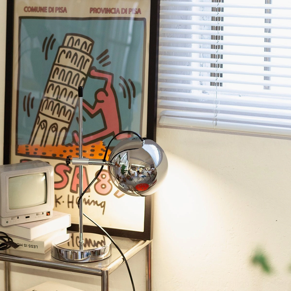 Chrome polished ball bracket desk lamp low-angle shot with vintage home decor backdrop