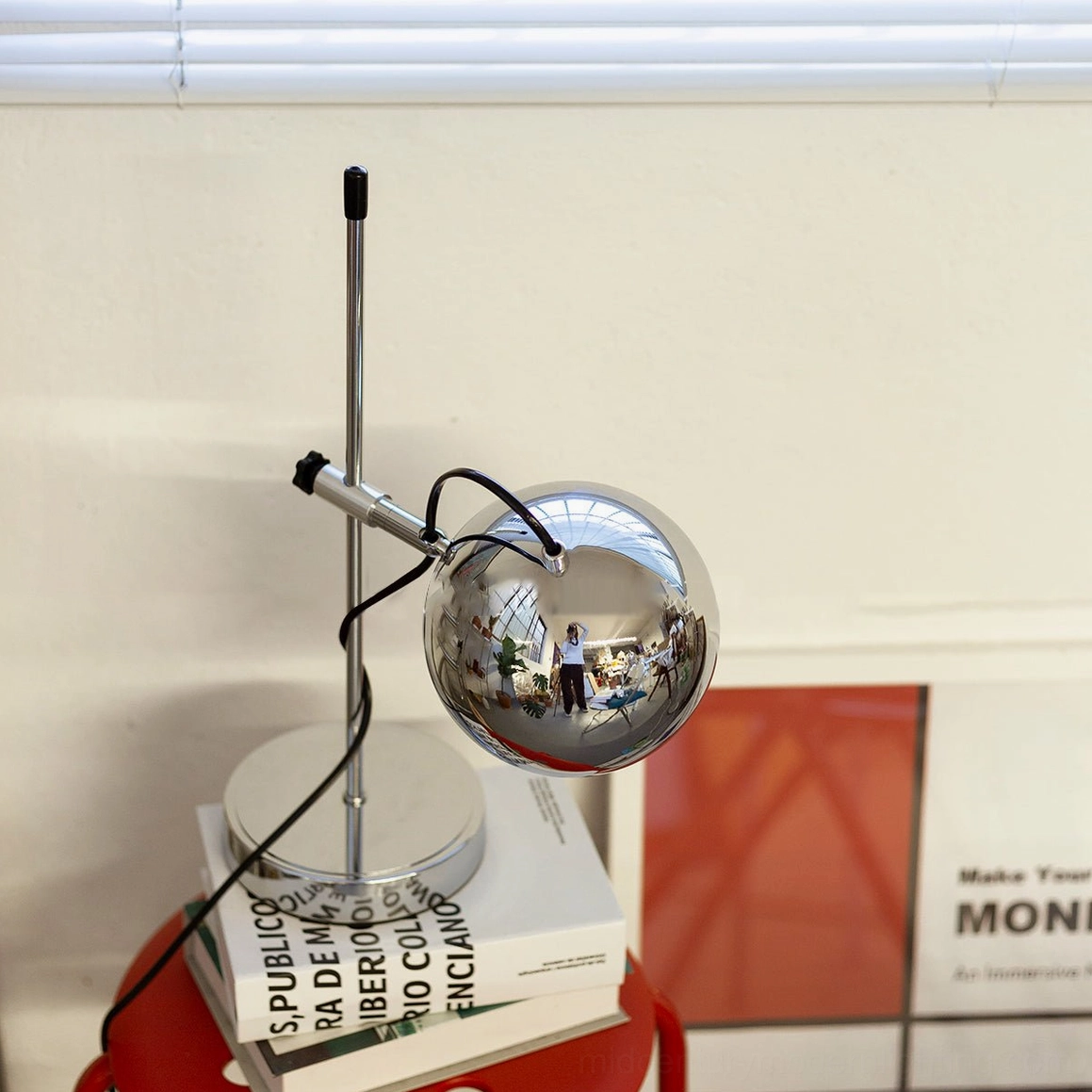 Chrome silver reflective spherical ball bracket table lamp beside stacked books