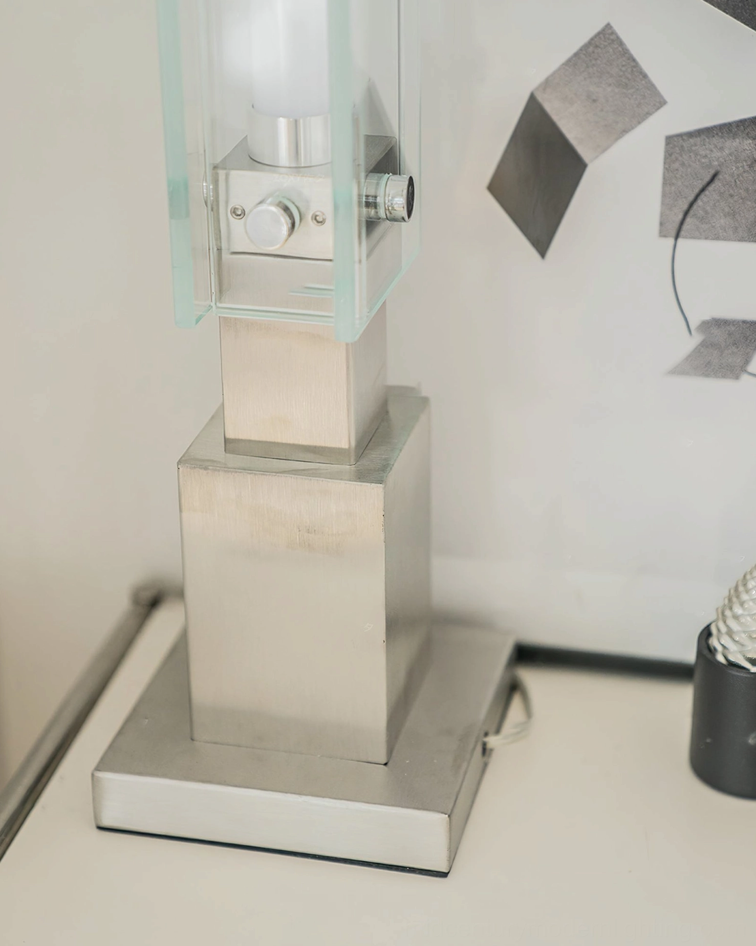 Detailed view of brushed chrome stainless steel base with geometric form of modern table lamp