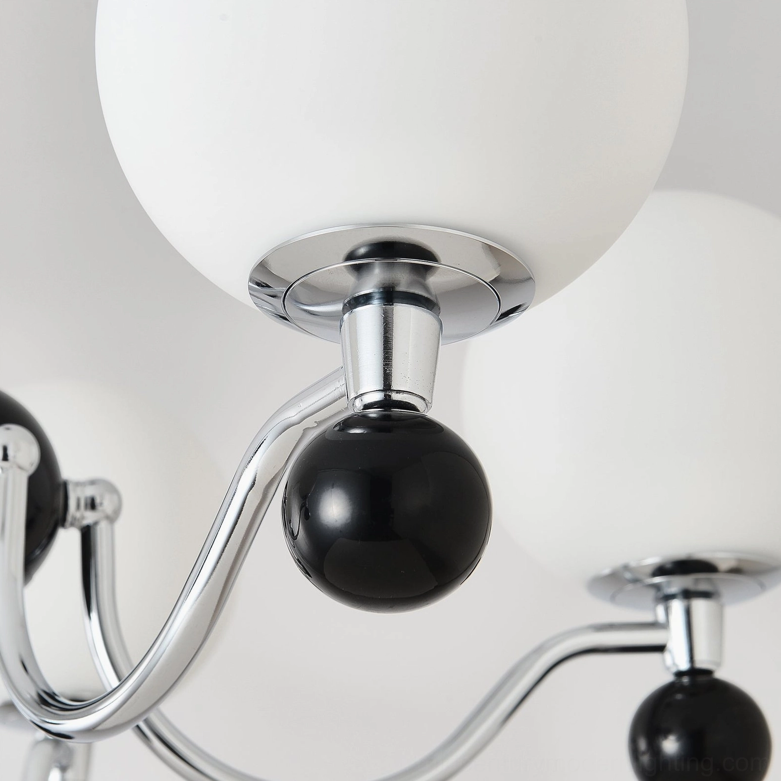 Modern chrome chandelier with black accent spheres and frosted glass shades side angle