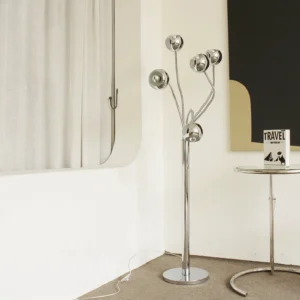 Chrome eyeball floor lamp styled in minimalist modern interior with round metal side table and neutral wall decor
