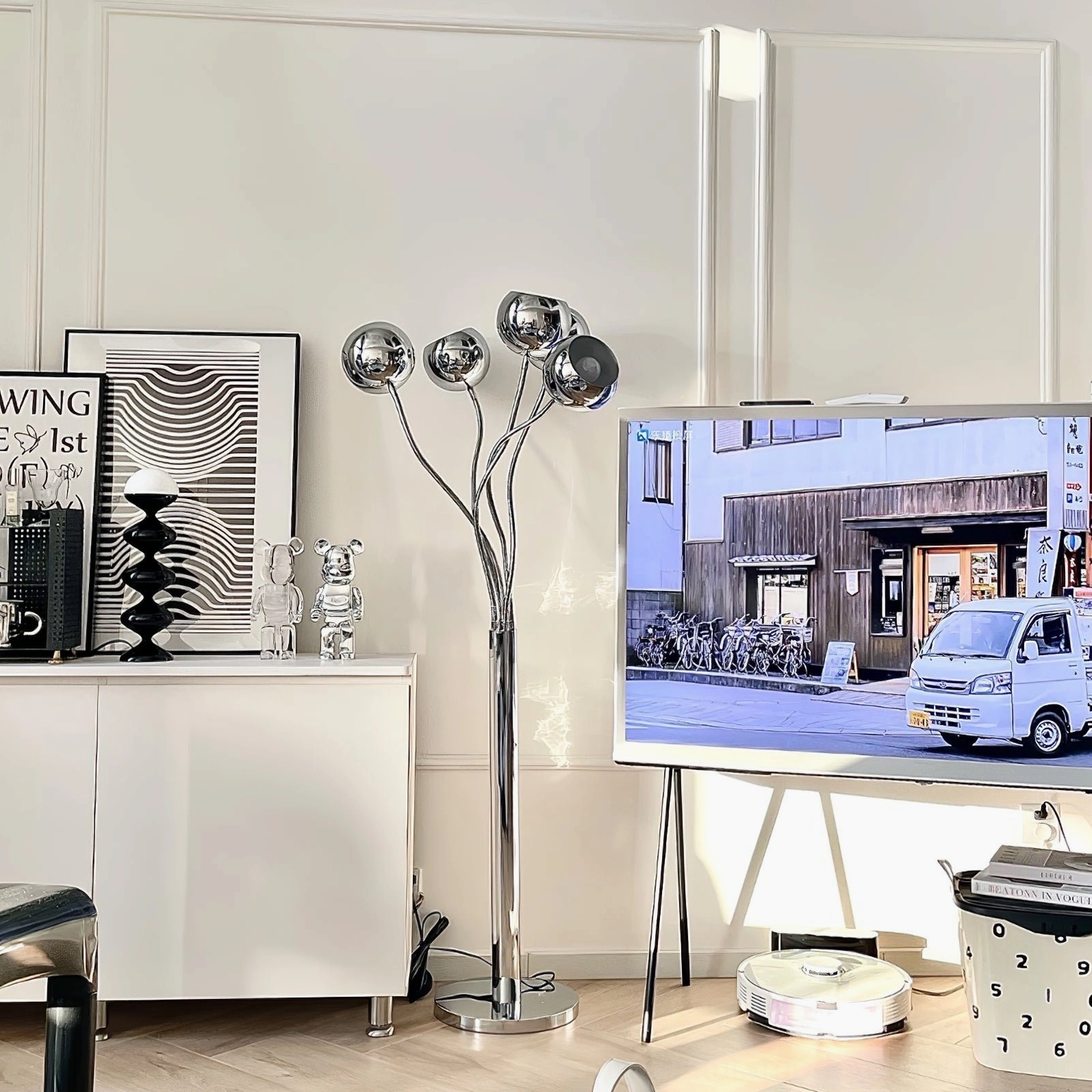 Chrome eyeball floor lamp in modern home display area with polished silver finish beside minimalist side cabinet