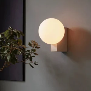 Contemporary globe wall lamp with off-white metal base and warm-glowing frosted glass shade in modern living room interior