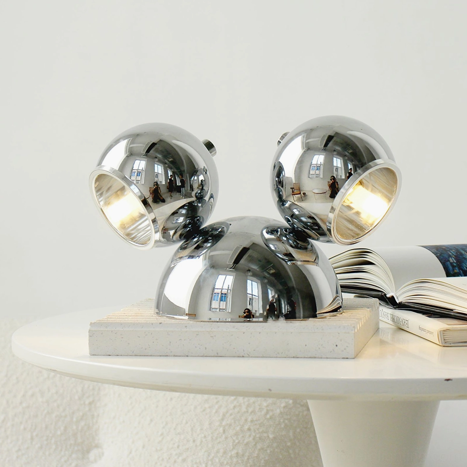 Sleek chrome Mickey table lamp side profile on minimalist white round side table contemporary decor