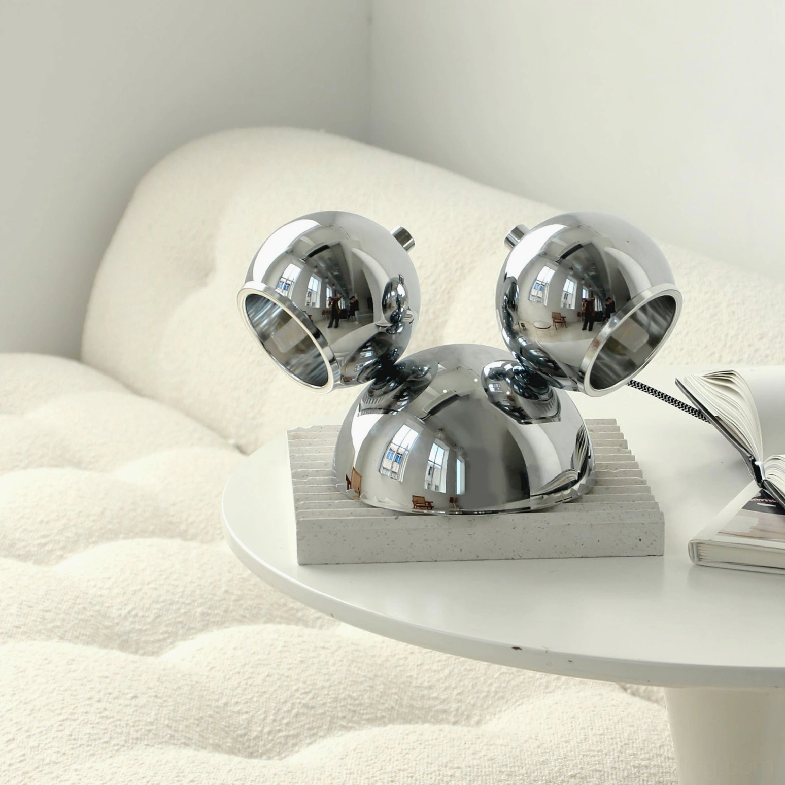 Polished chrome Mickey table lamp on tufted sofa side table neutral contemporary home setting