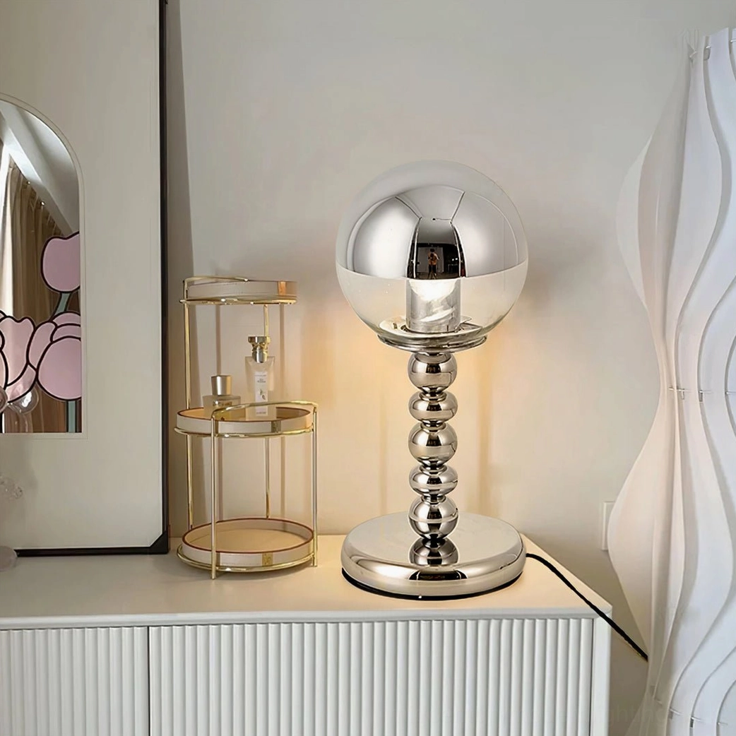 Chrome Mirrorball table lamp with beaded stem positioned on bedroom vanity cabinet, modern design