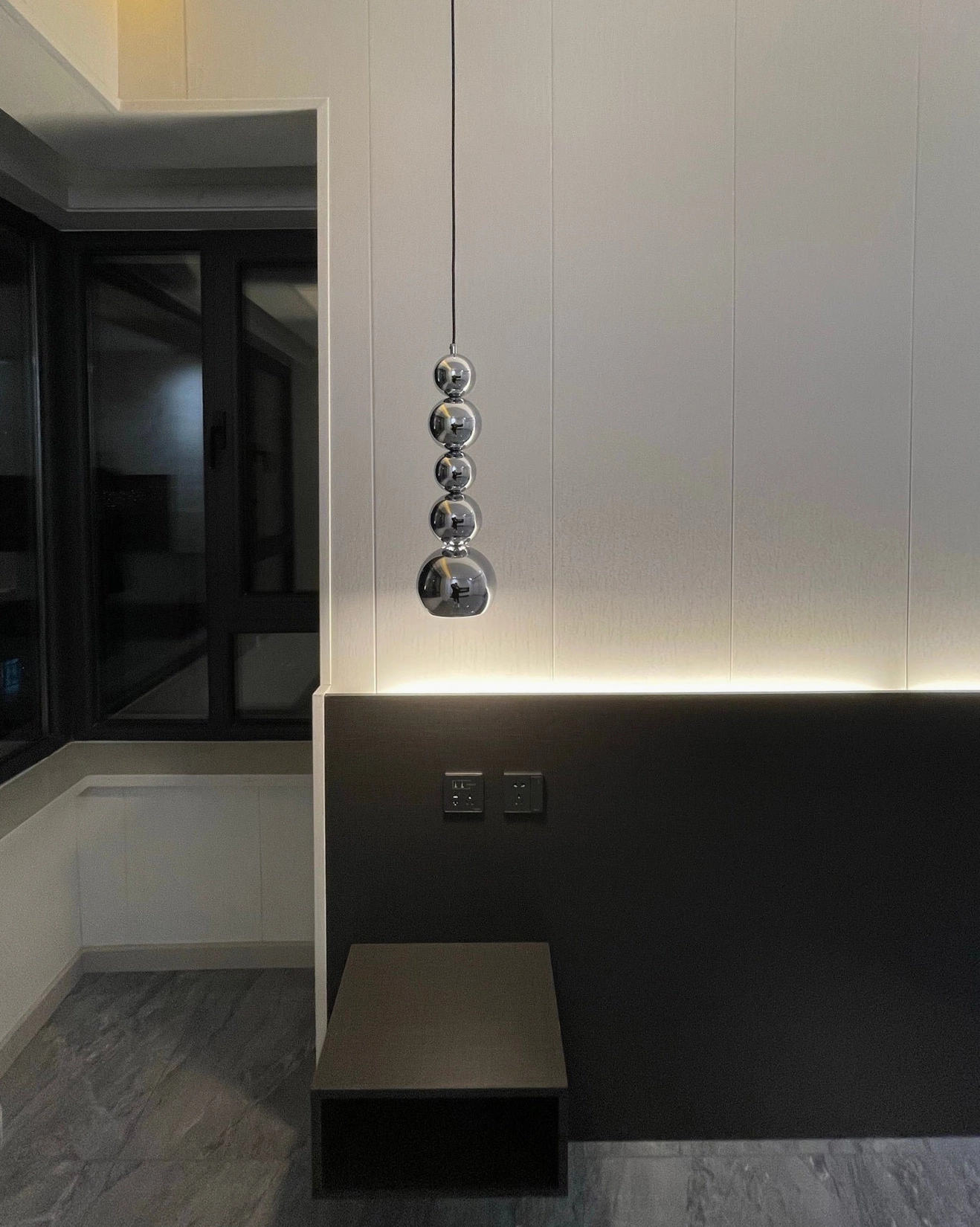 Vertical stacked ball pendant light in modern bedroom with dark accent wall, sleek chrome spherical design