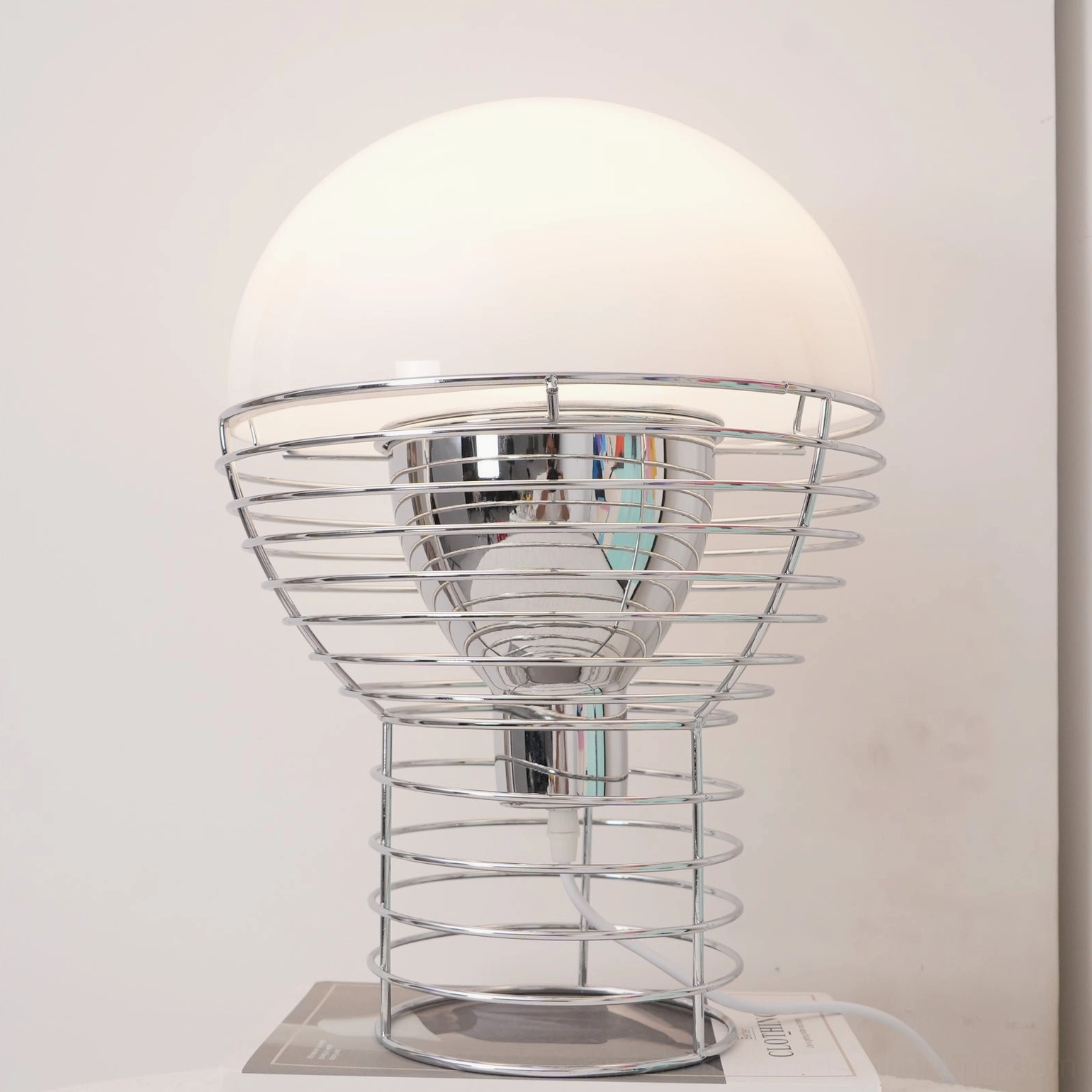 Front close-up of polished chrome wire cage table lamp on display platform