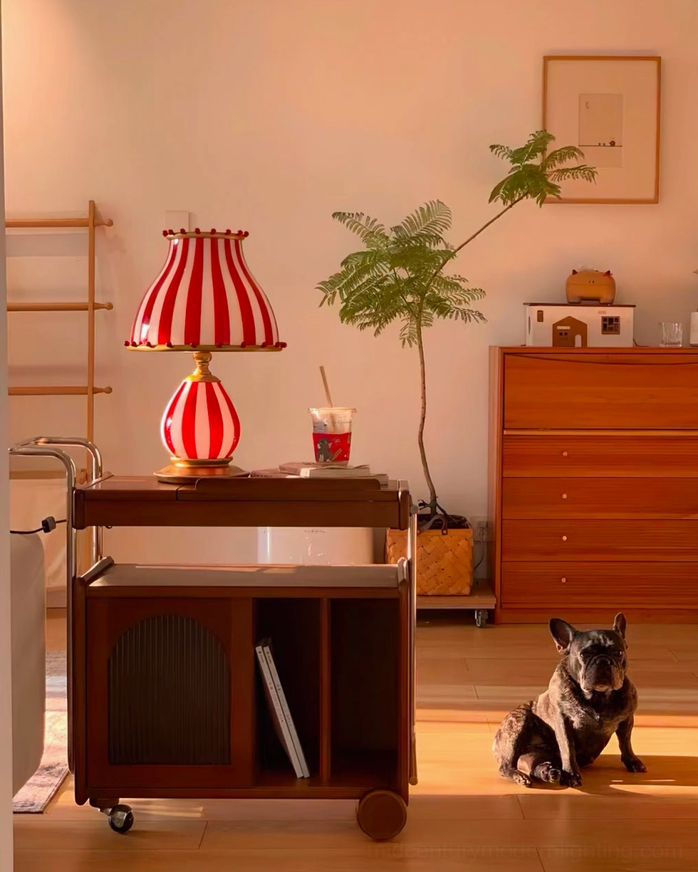 Red and white striped circus lamp in minimalist bedroom corner with dog and potted plant