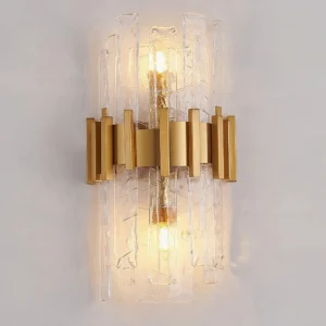 Modern gold wall sconce with rippled glass shades installed on beige interior wall, lit view