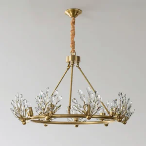 Clara Crystal Chandelier neoclassical design featuring clear crystal accents and warm brass finish against light gray indoor wall, front view demonstration