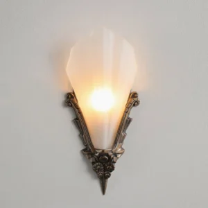 Close-up view of Claridge sconce showing carved bronze hardware and flared frosted glass shade with warm light
