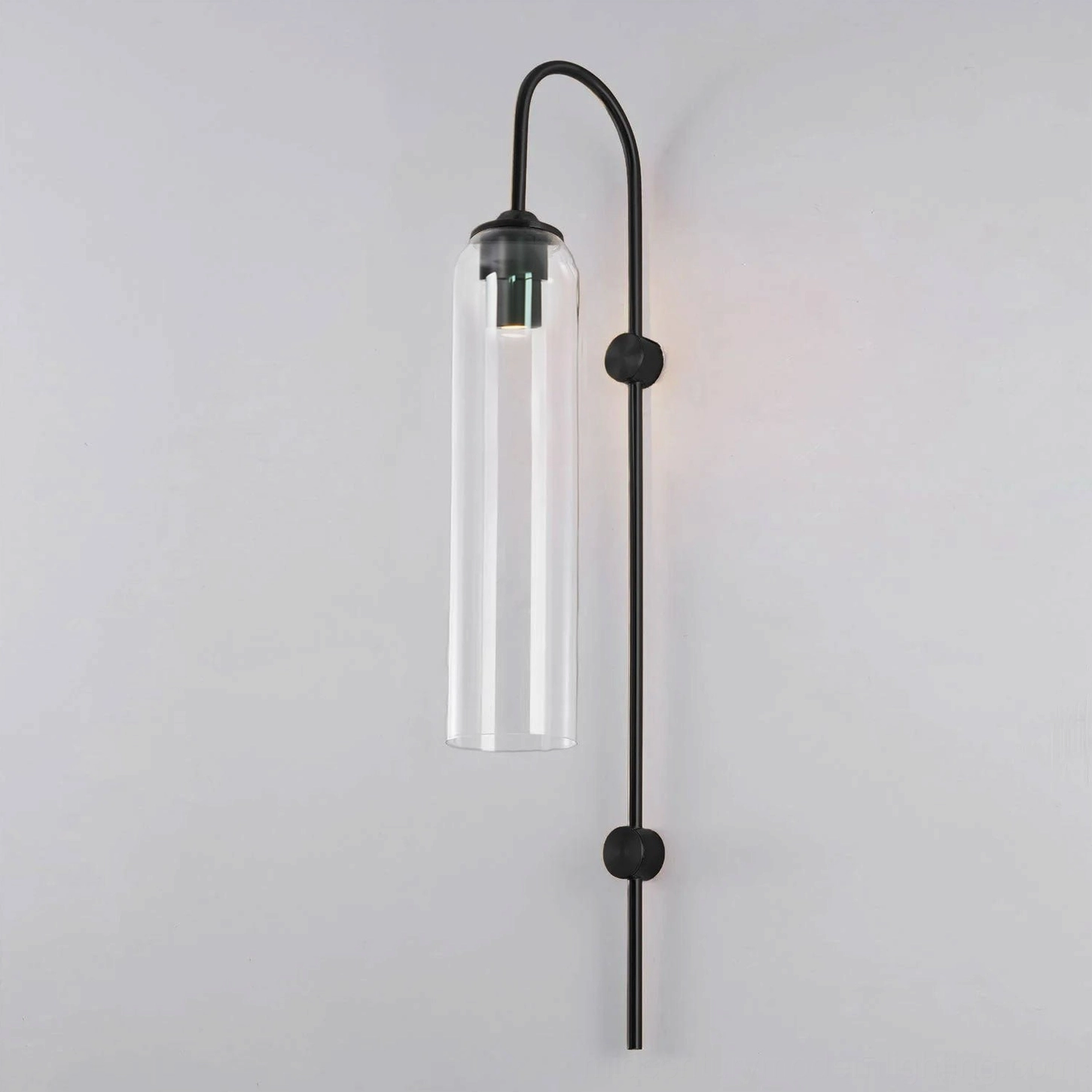 Clear glass wall sconce with black metal frame in modern minimalist interior setting