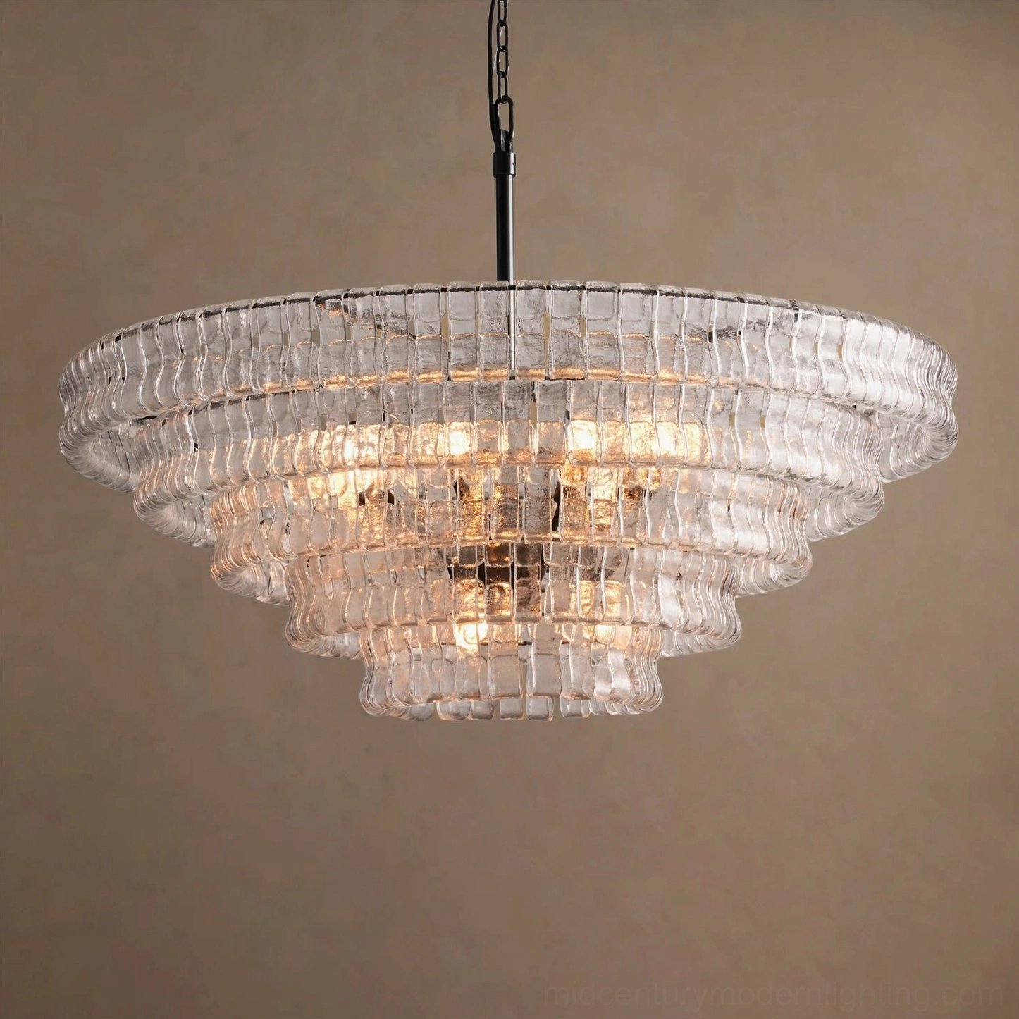 Clear ice-textured tiered round chandelier, close-up overhead view with polished brass hardware on neutral background