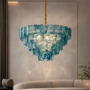 Blue tiered glass chandelier overhead view in modern living room, fabric-wrapped hanging rod, artistic pendant lighting installation