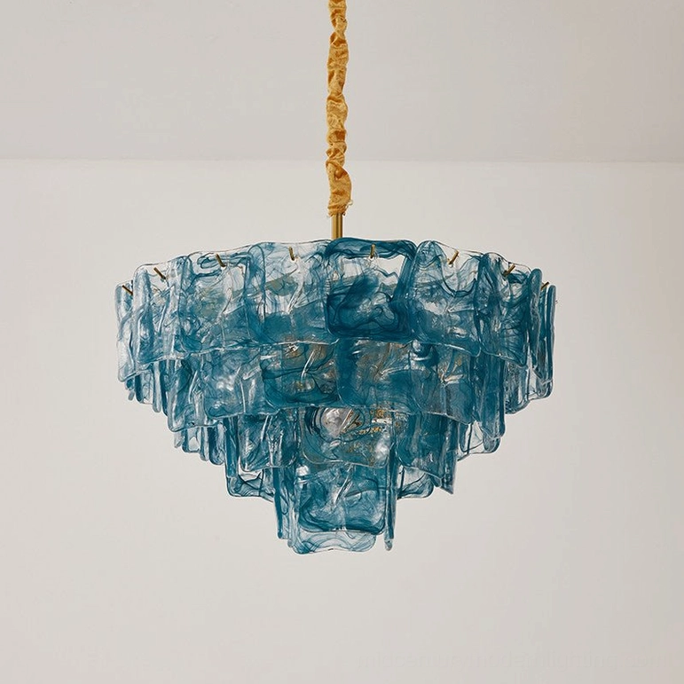 Compact three-tier blue art glass chandelier with brass fabric-wrapped suspension rod, hanging studio view, mid-century modern lighting