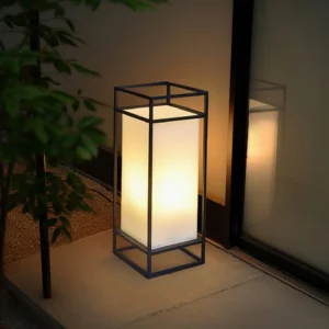 Cleo outdoor lantern illuminated at residential entrance nighttime three-quarter angle