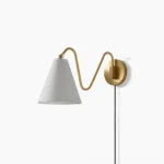Cleome swing arm wall lamp with brass curved arm and white fabric shade on white background studio shot
