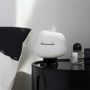 Cloud Night bedside lamp styled on minimalist bedroom nightstand with modern black and white bedding, paired with glass perfume bottle