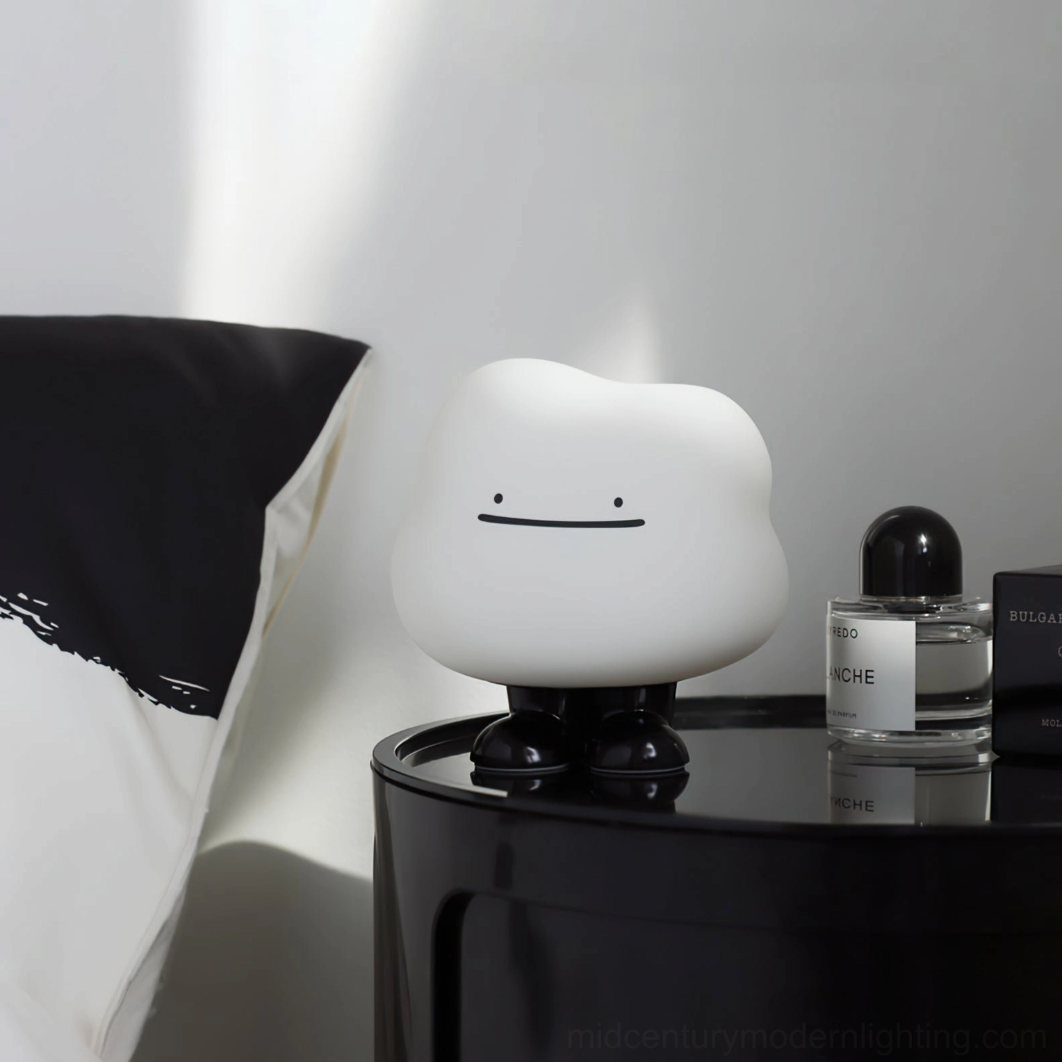 Cloud Night bedside lamp styled on minimalist bedroom nightstand with modern black and white bedding, paired with glass perfume bottle