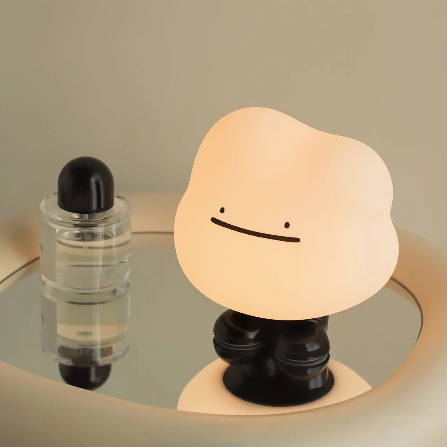 Illuminated Cloud Night portable LED lamp glowing warm white light on mirrored round bedside table with perfume bottle accent