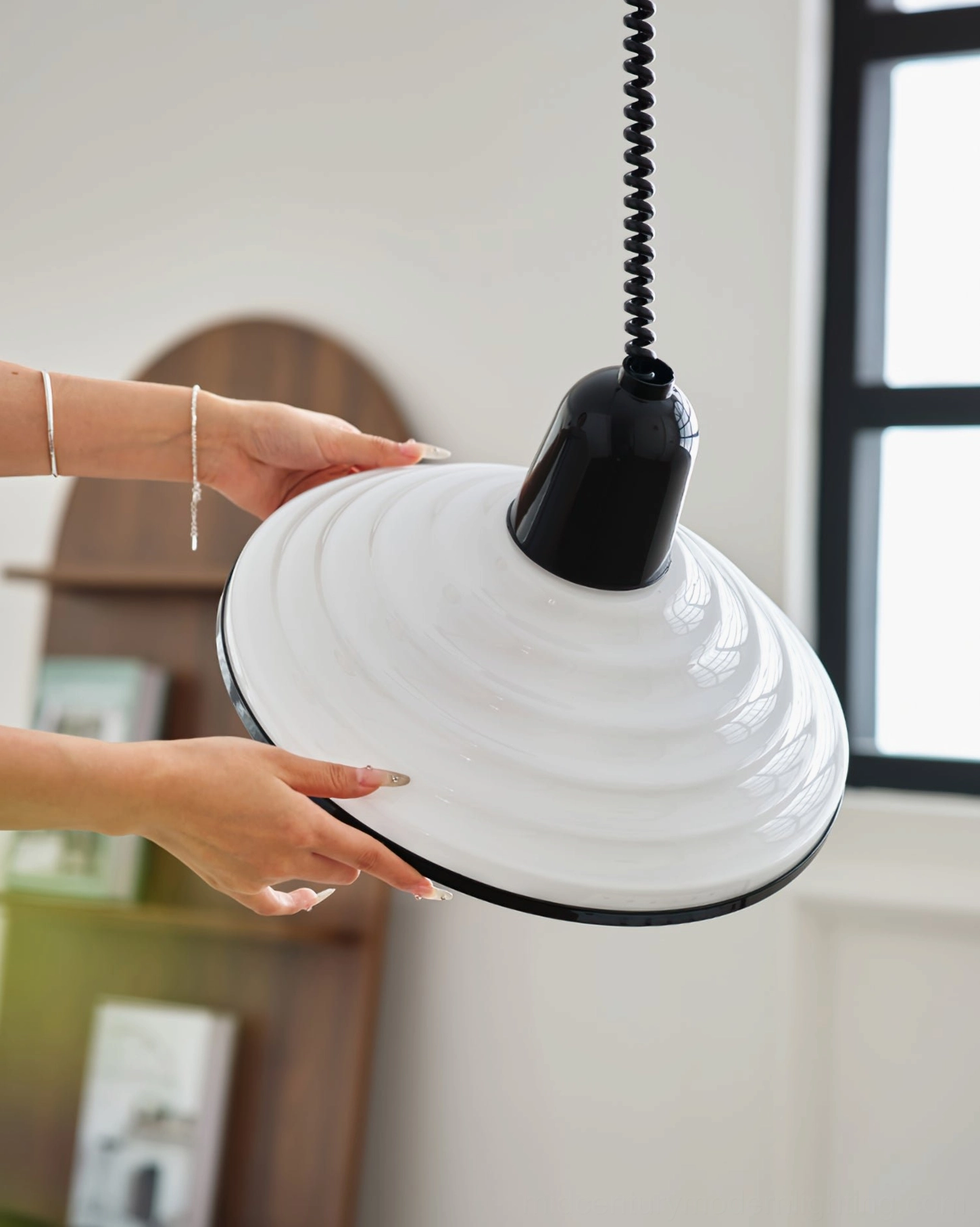Hands adjusting mid-century modern ridged pendant lamp fixture in living room setting
