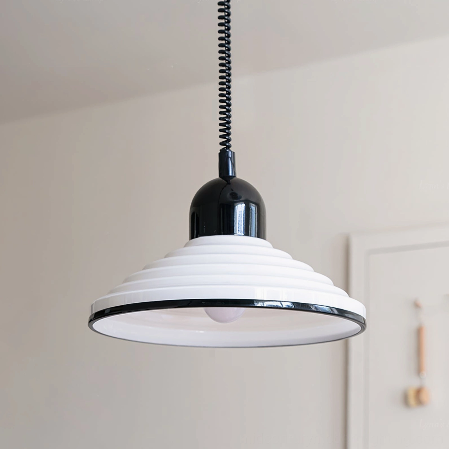 Codialpo pendant light suspended over kitchen counter three-quarter angle with coiled cord and black hardware