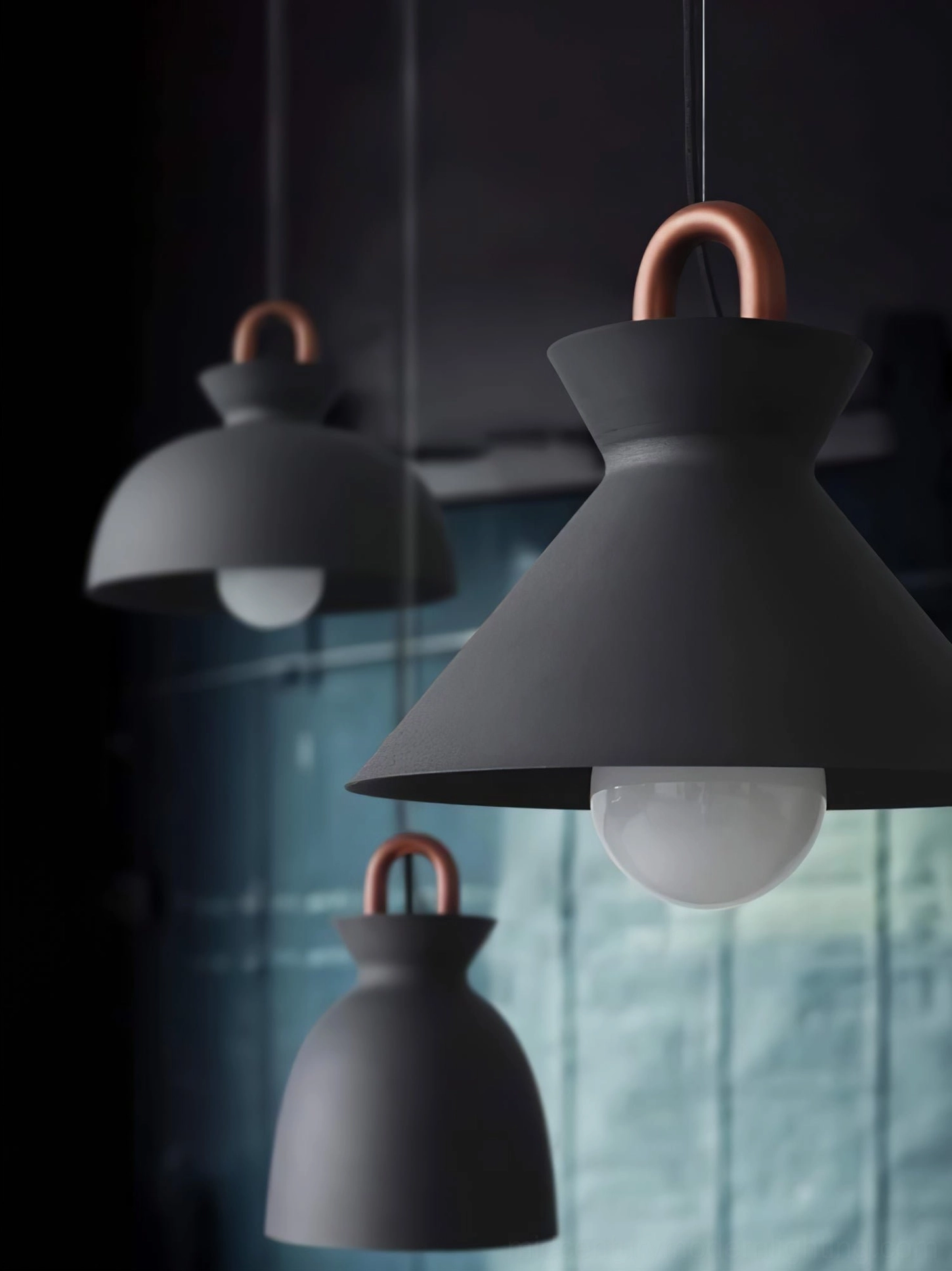 Multiple black coil pendant lights in varying sizes with copper loops low-angle hanging view