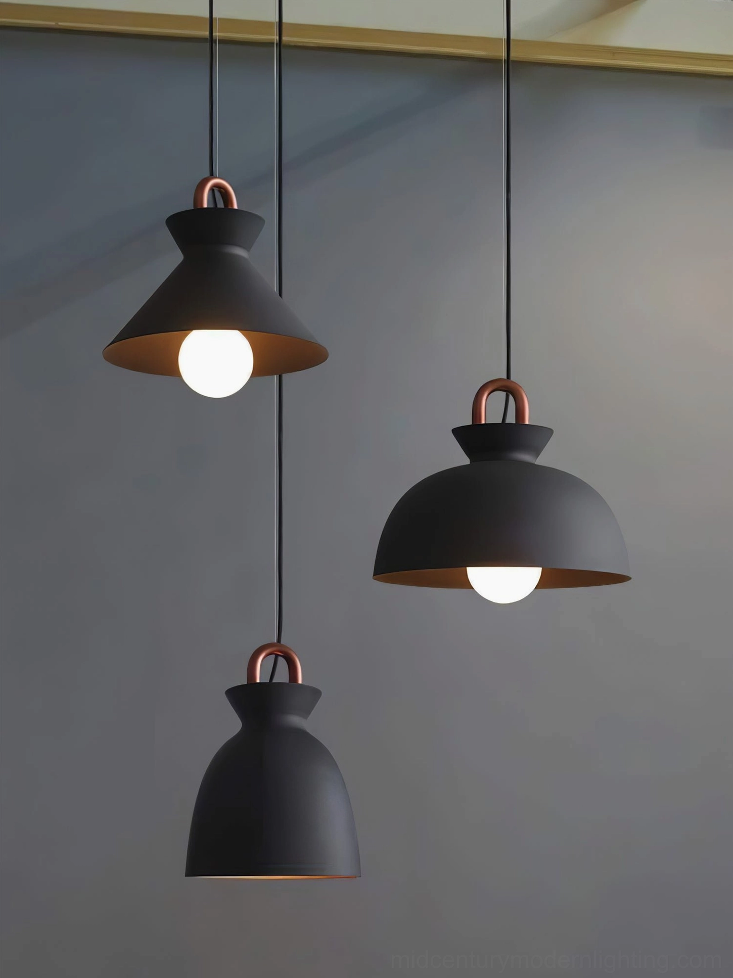 Multiple black coil pendant lights in different shapes displayed together on grey wall