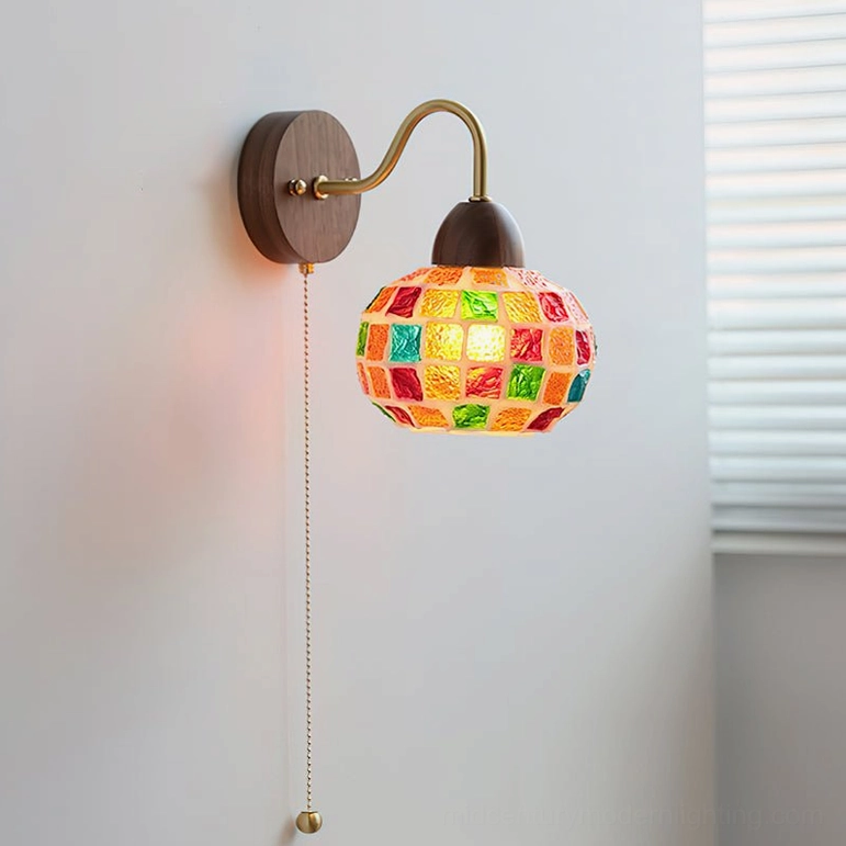 Vibrant color-block mosaic wall lamp with red, green, and blue glass tiles and walnut wood fixture on bedroom wall