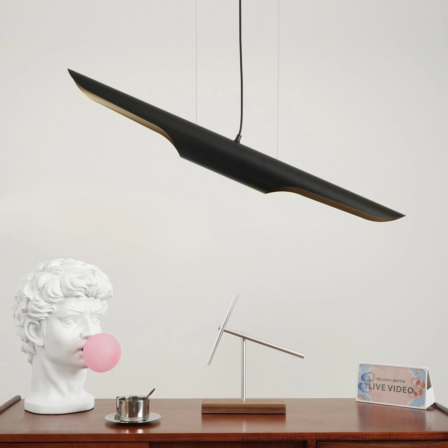 Coltrane pendant light illuminated above wooden desk with decorative elements in modern interior