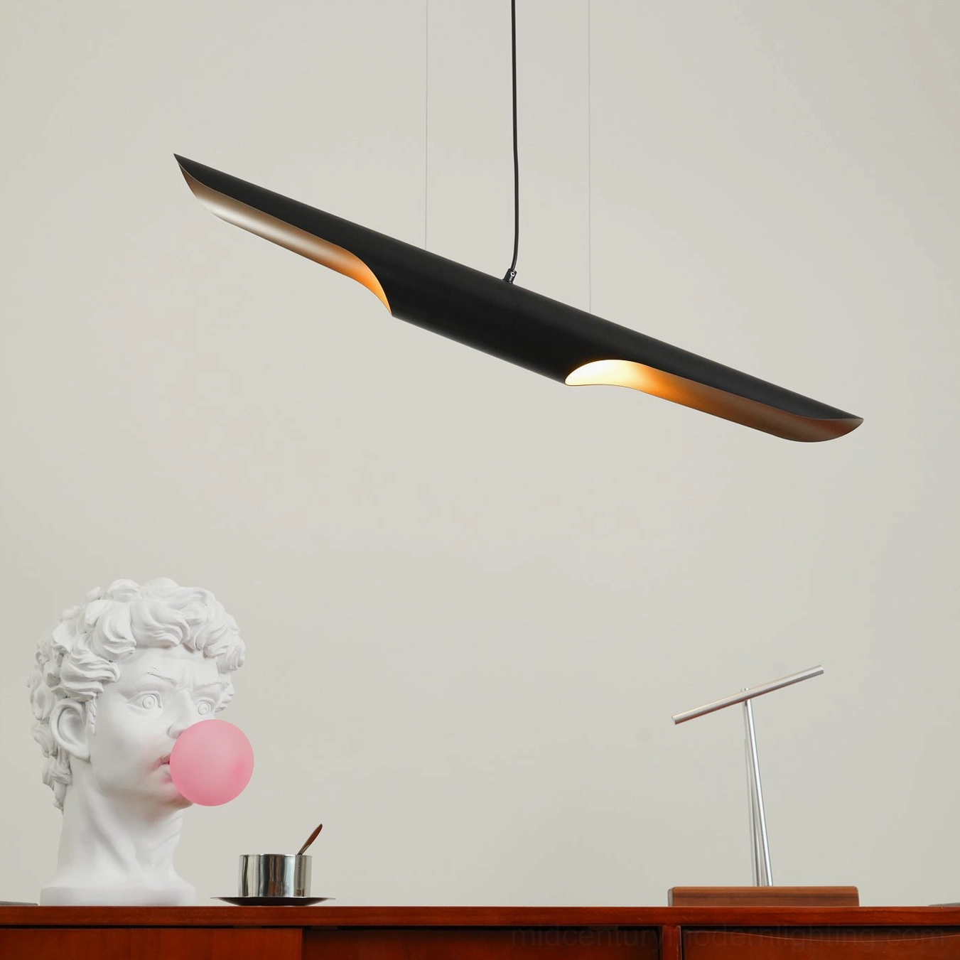 Warm gold interior light emission of Coltrane modern pendant lamp against neutral wall