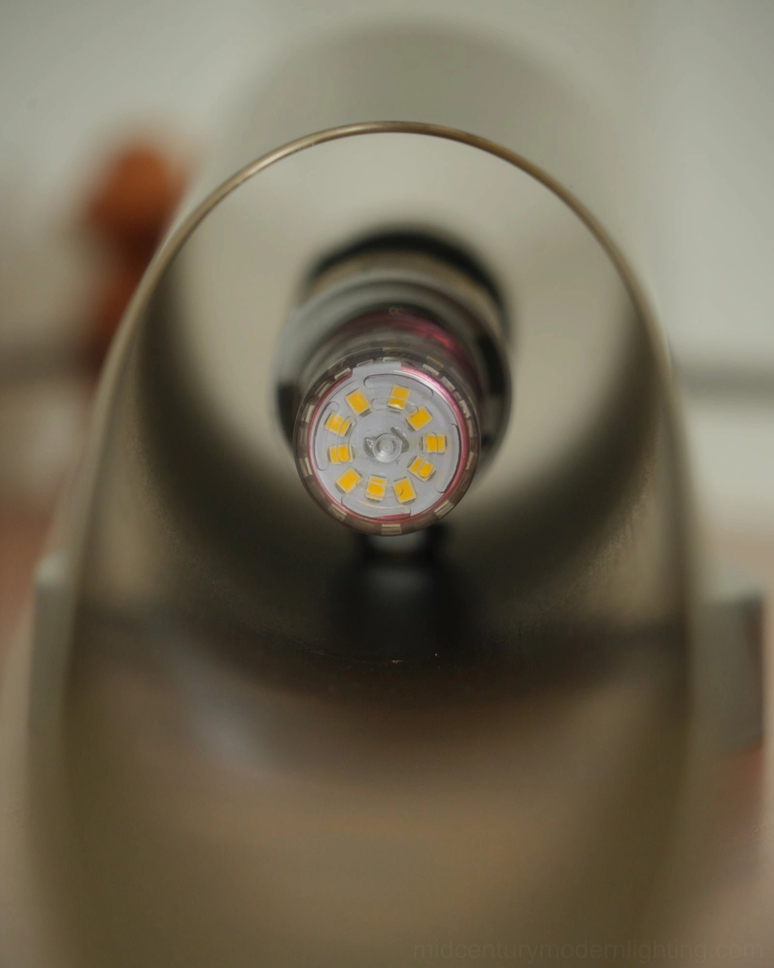 Coltrane wall sconce macro shot showing LED bulb inside metal housing bronze coating