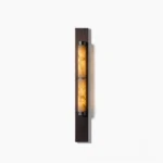 Columnar alabaster wall sconce with brass backplate on white background, modern minimalist design
