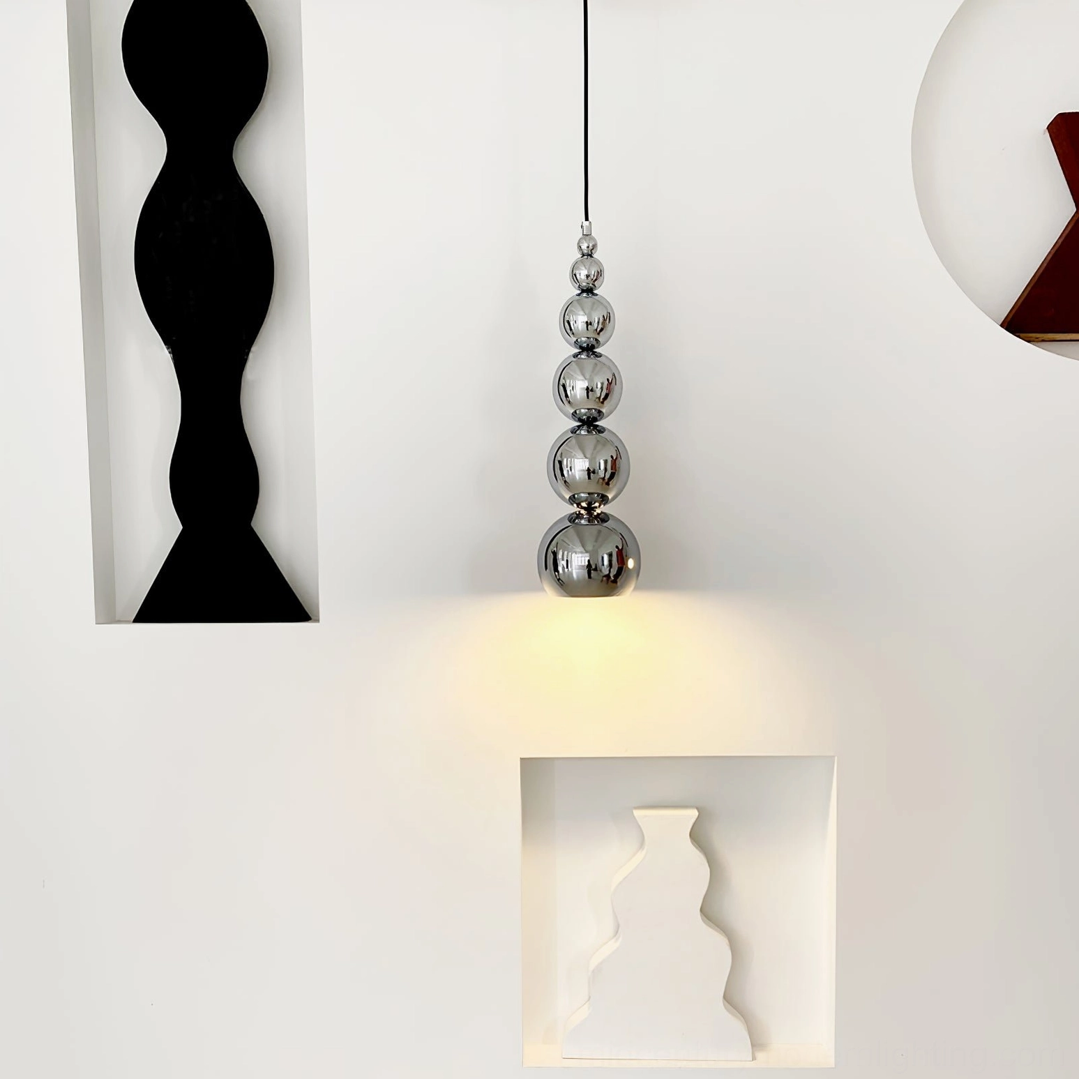 Small stacked chrome sphere pendant light above decorative wall niches, minimalist modern design fixture