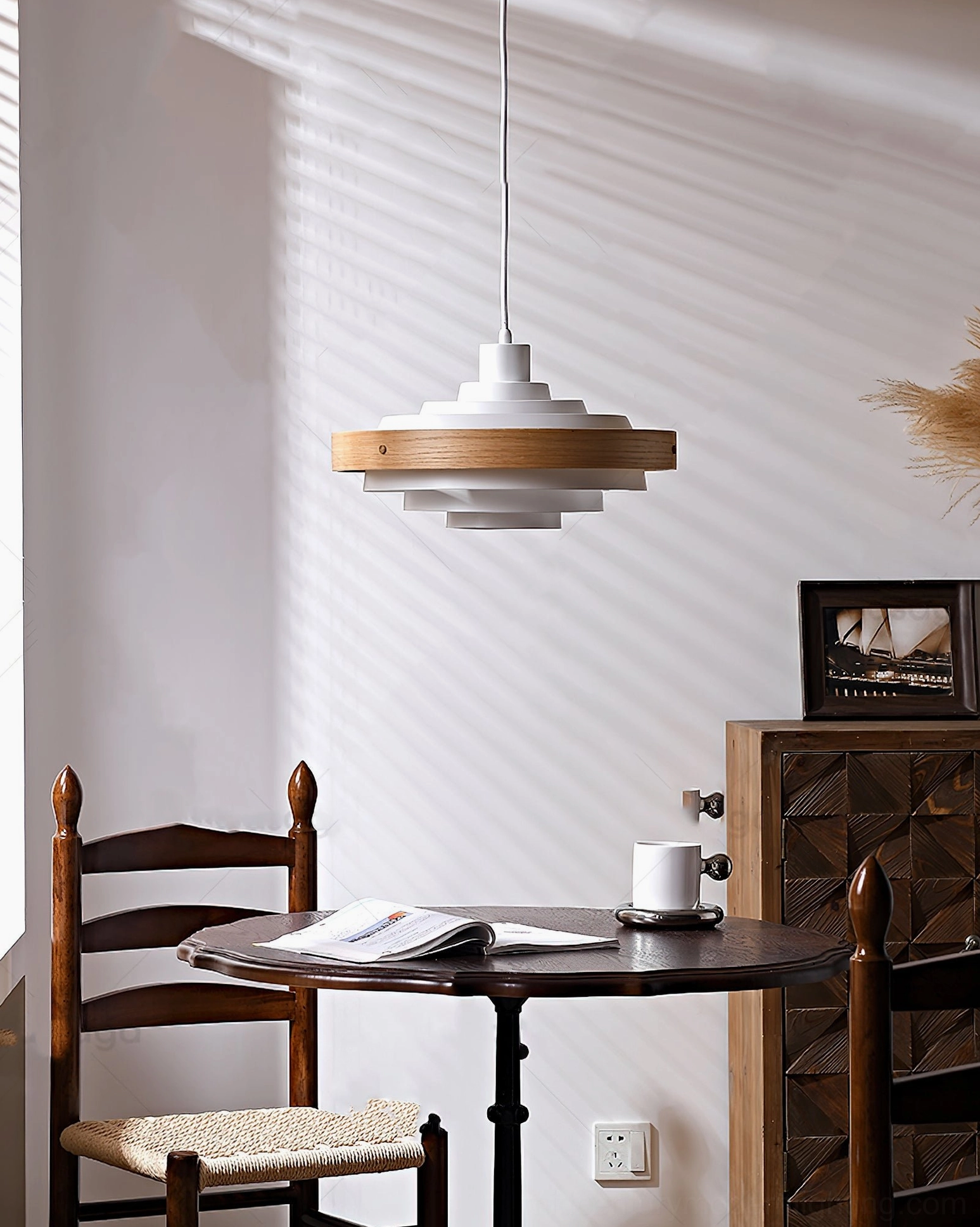 Layered pendant light with white and light wood shade in compact home dining corner