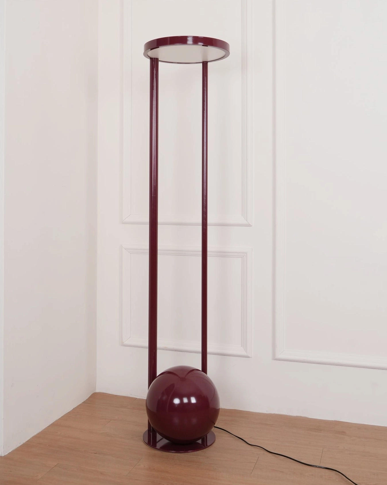 Red composition floor lamp positioned in modern room corner - sculptural form with visible metal spherical base and support structure