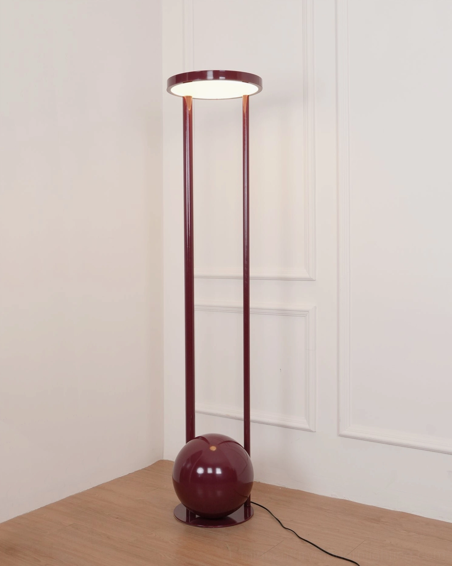Lit composition red floor lamp in contemporary paneled room - glowing circular diffuser casting warm illumination in corner setting