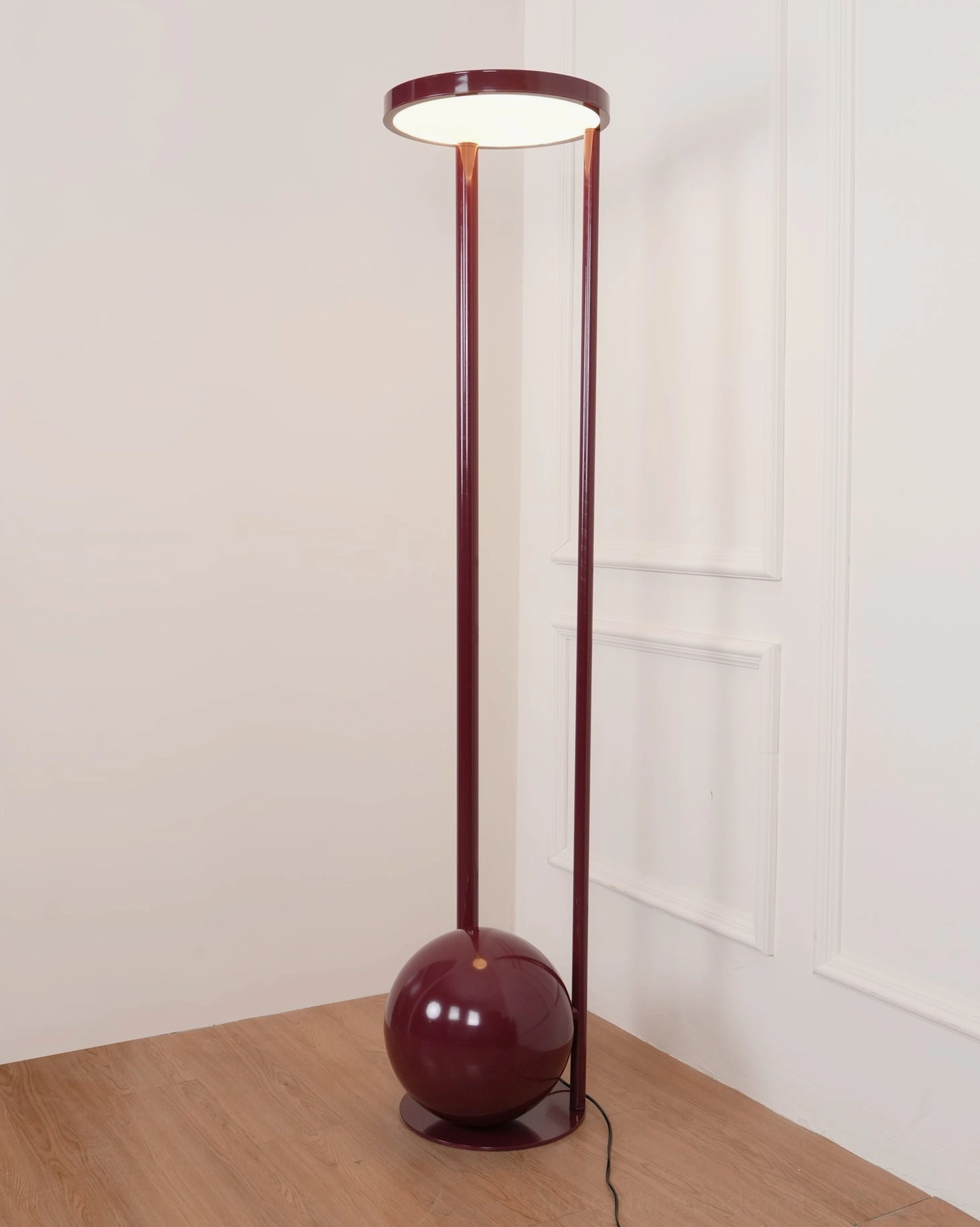 Illuminated composition floor lamp front corner view - burgundy metallic form with lit acrylic diffuser in modern paneled interior