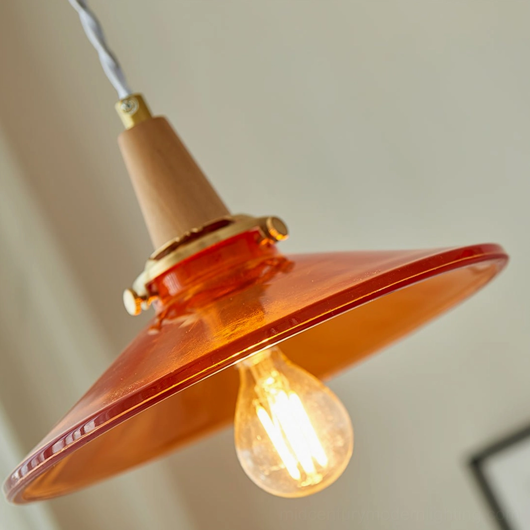 Amber glass pendant lamp mounted in minimalist contemporary interior with neutral wall tones and decorative elements