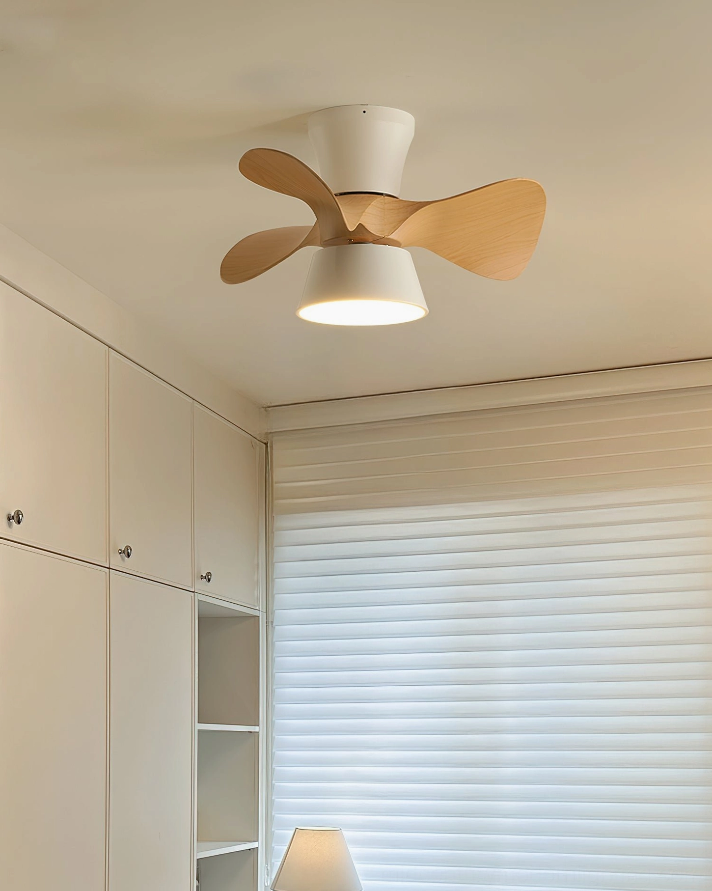 Low-angle view of modern ceiling fan light in contemporary study room with warm wood grain blade detail and soft illumination